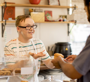 Junger Mann mit Behinderung arbeitet in Café
