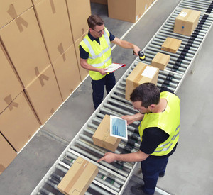 Zwei Arbeiter in einem Lager in der Logistikbranche, der Pakete am Fließband verarbeitet